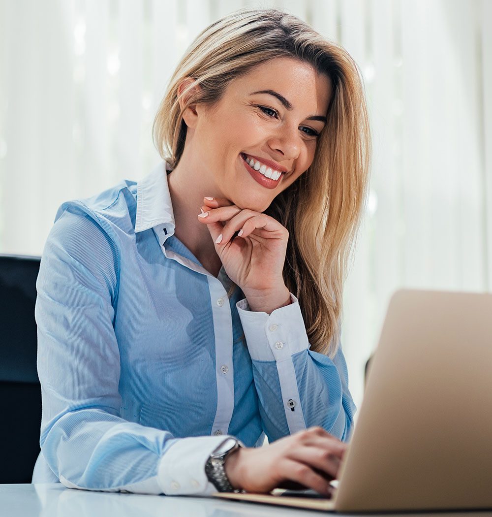 Profissional sorrindo em frente ao notebook enquanto trabalha