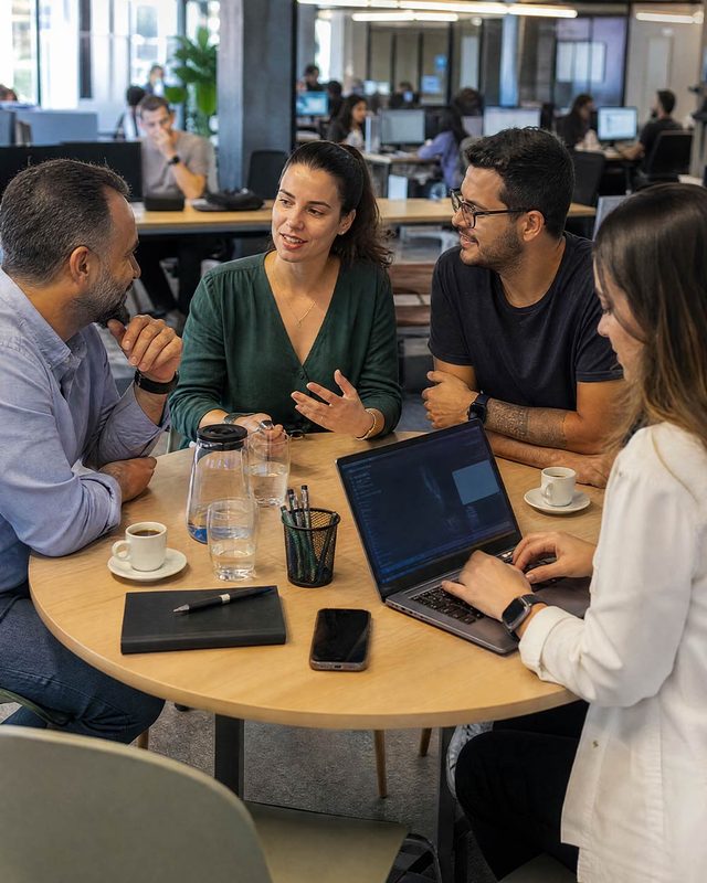 Equipe da Zoomi reunida com clientes em uma mesa de trabalho