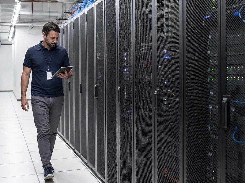 Técnico com tablet monitorando racks de servidores em um data center